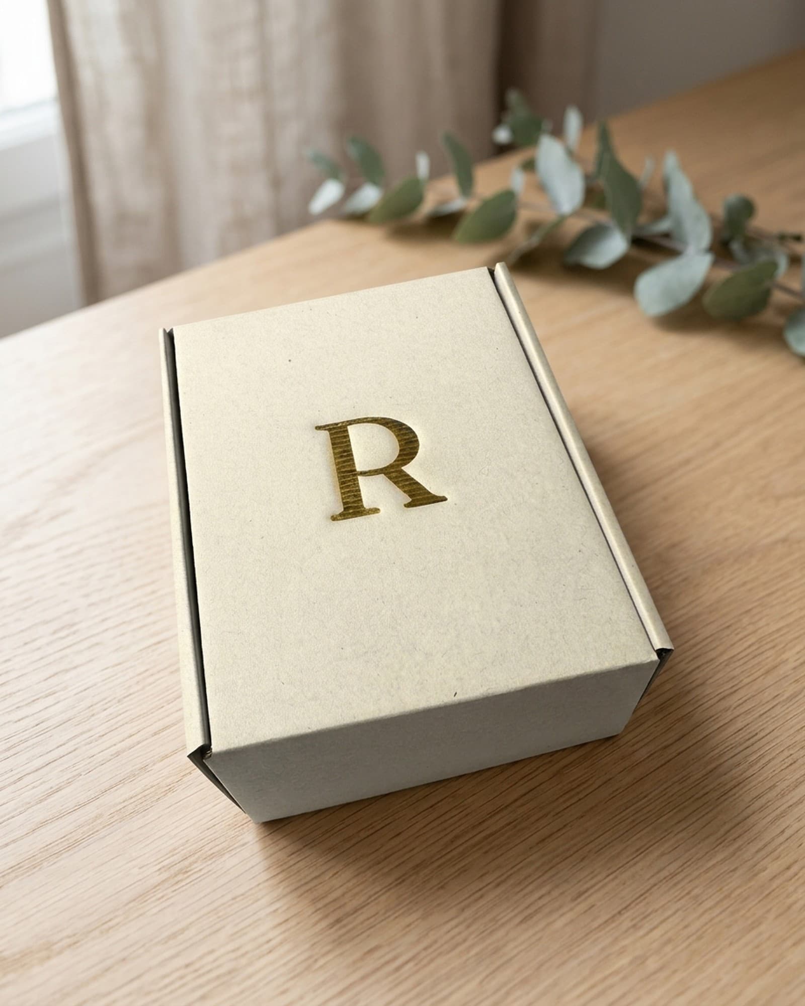 Coffret Rhealiz, probiotique et prébiotique fabriqué en France, monogramme R doré, sur une table en chêne