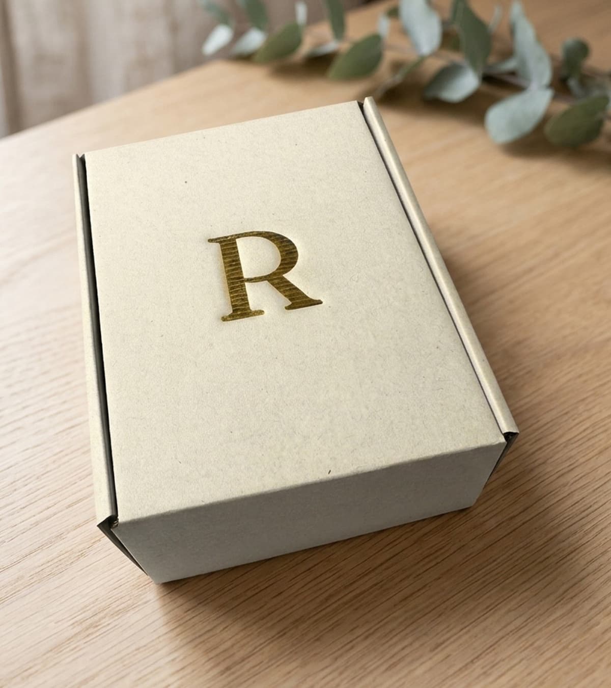 Coffret Rhealiz, probiotique et prébiotique fabriqué en France, monogramme R doré, sur une table en chêne